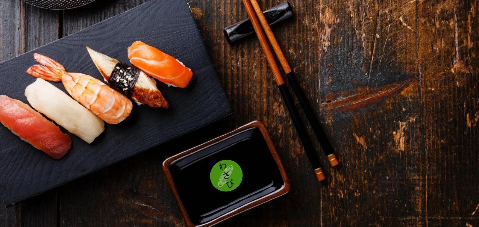 Nigiri sushi on a slate plate beside chopsticks and soy sauce