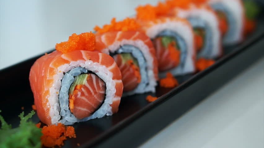 Salmon sushi roll on a dark serving plate