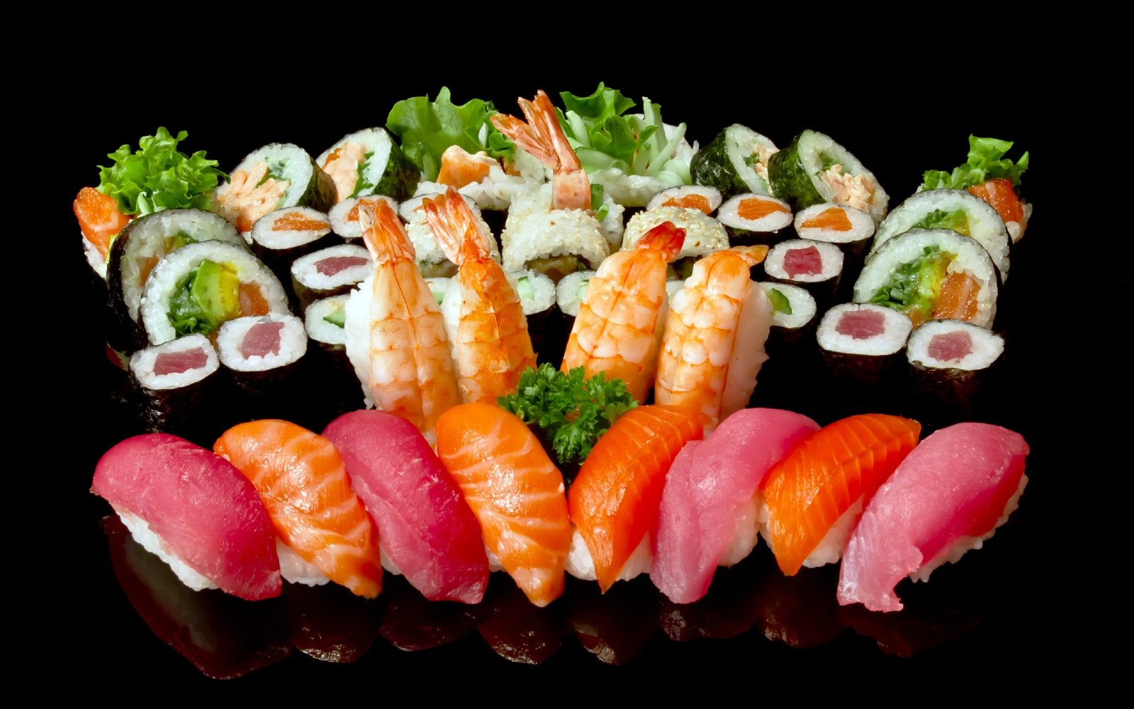 Large assortment of nigiri, maki and shrimp sushi on a black background